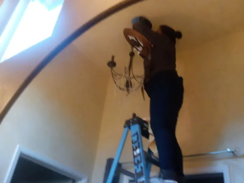 Electrician installing a chandelier in a Sturtevant residence